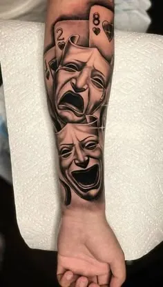 Black and grey forearm tattoo of comedy and tragedy masks with playing cards